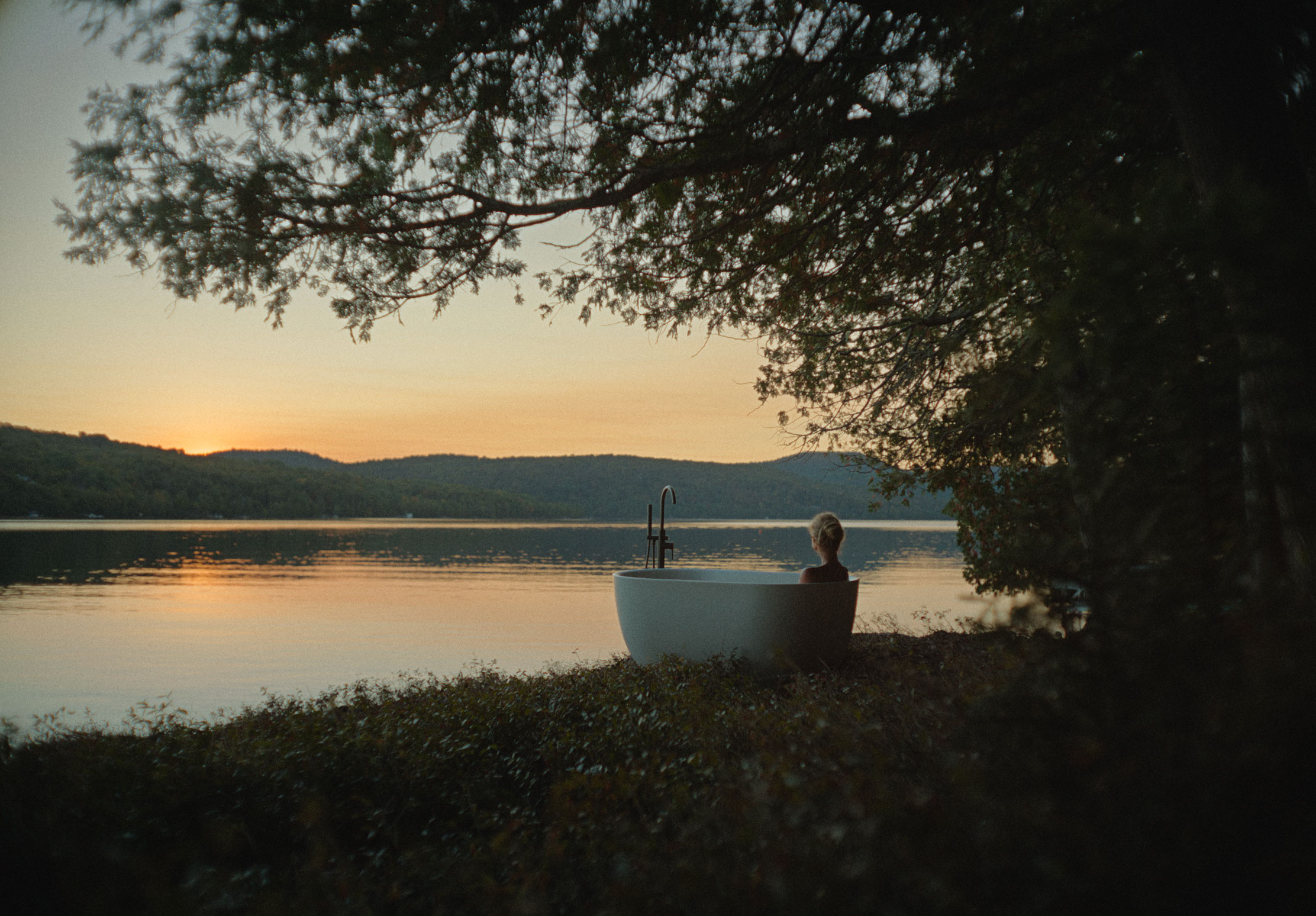 Outdoor bathtub overlooking a lake at sunset, cover photo for the Bonneville – Invisible Houses project